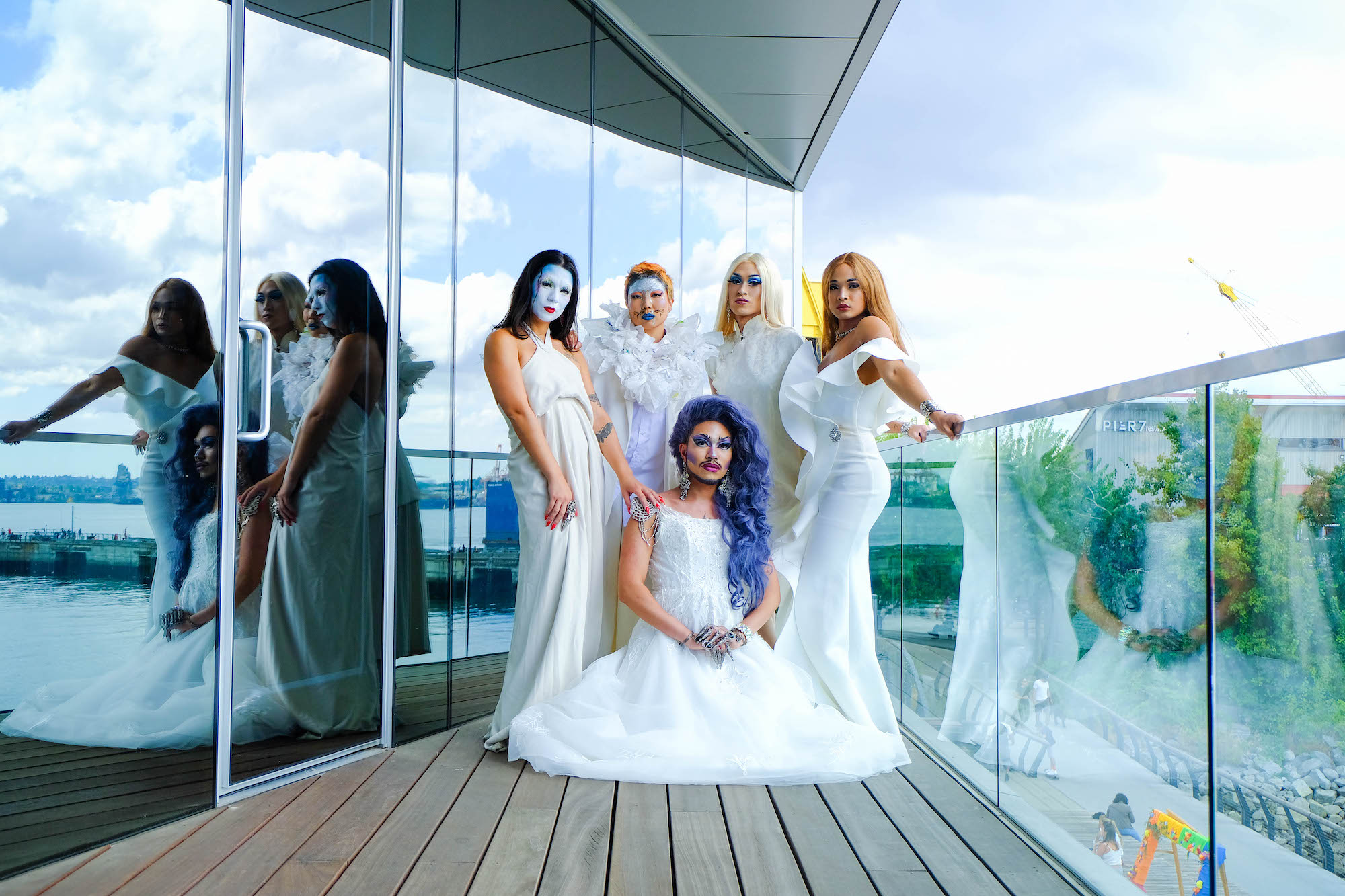 Five members of House of Rice, dressed in white, pose on the Polygon Gallery terrace, with four standing and one seated.