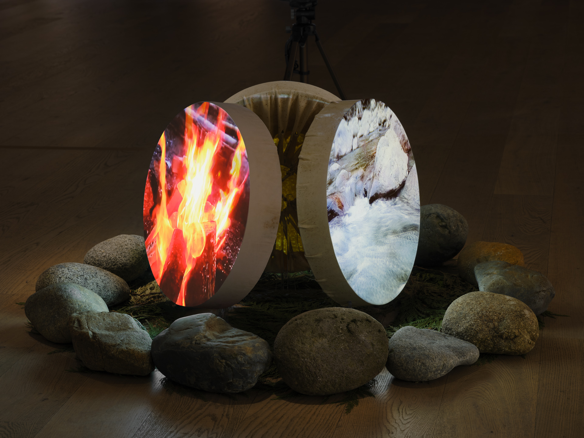 Three circular slabs of rock with images of fire, ice and forest stand balanced on their ends and each surrounded by a loose circle of smaller rocks surrounding them.